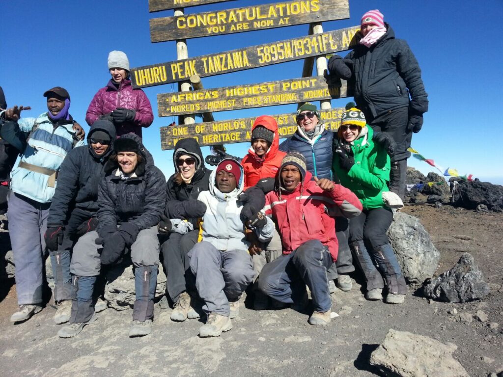 group of trekkers behind a congratulations post