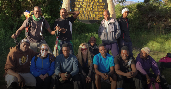 group of trekkers sitting behind a signage