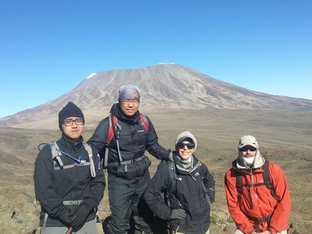 four trekkers posing in front of a mountain
